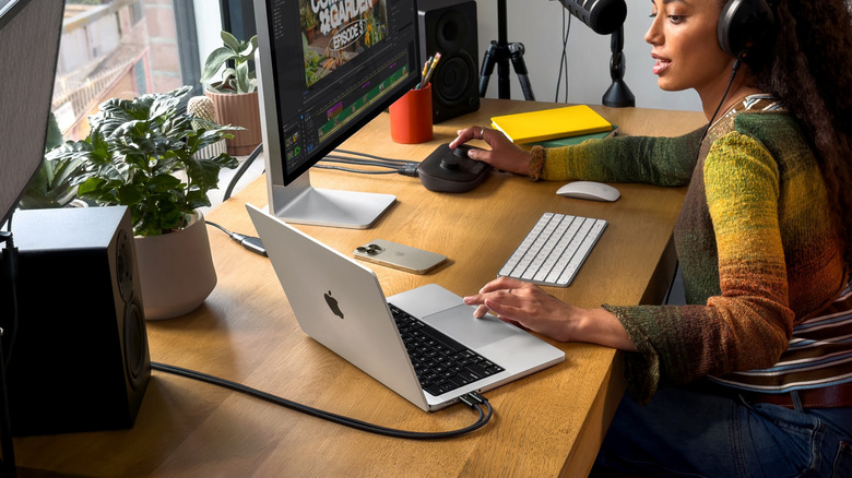 A person using the MacBook Pro M5 on a desk surrounded by other hardware
