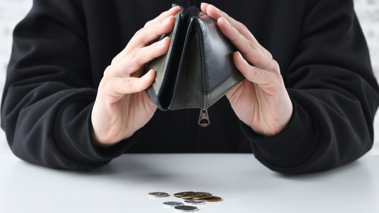 Man turns wallet upside down and only a few pennies inside