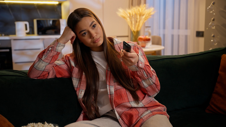 a frustrated woman watching TV on her sofa