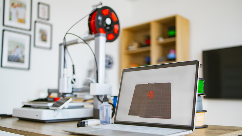 A home 3D printer connected to a laptop.