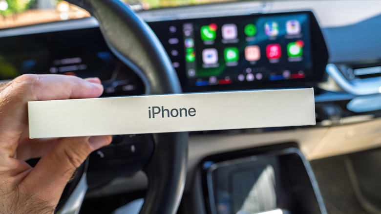 An iPhone box in front of an Apple CarPlay system in a car