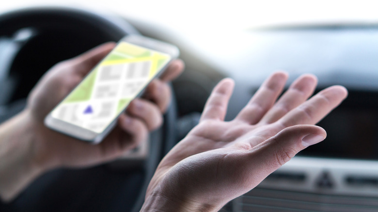 a person's hands holding a navigation app on their phone and being confused