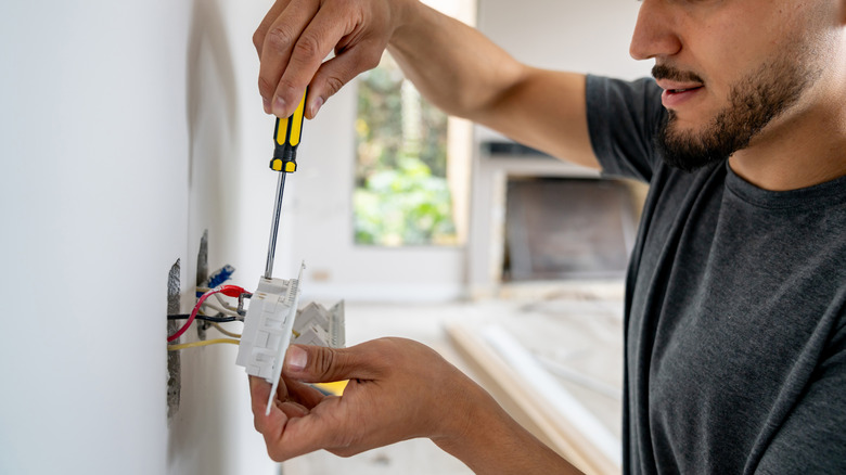 An electrician installing a power receptacle in a modern home.