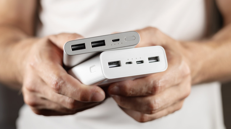 Person holding two power banks showing USB-A and USB-C charging ports
