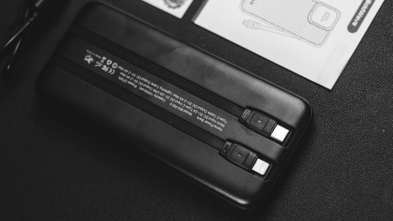 A power bank placed upside down on a black surface showing the model name, input voltage, and output voltage