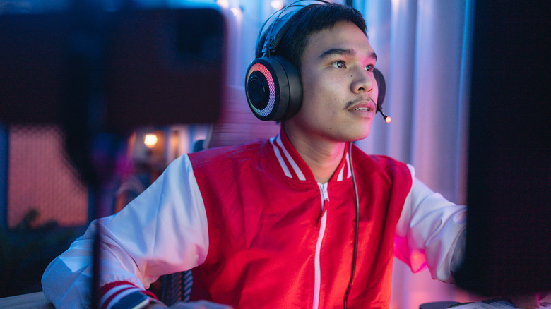a young man PC gamer on a headset looking at his computer