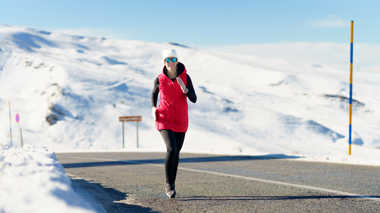 A woman jogging in a snowy landscape wearing polarized sunglasses