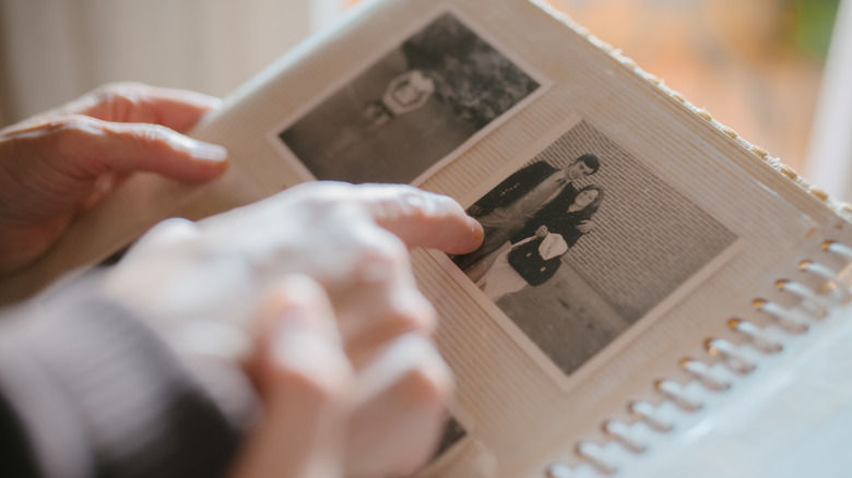 Hands pointing at photos in an old photograph book