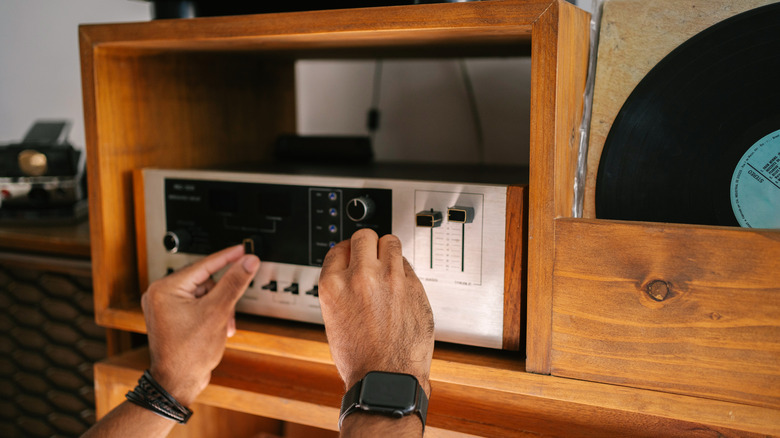 Hands adjusting audio equipment in a home setup