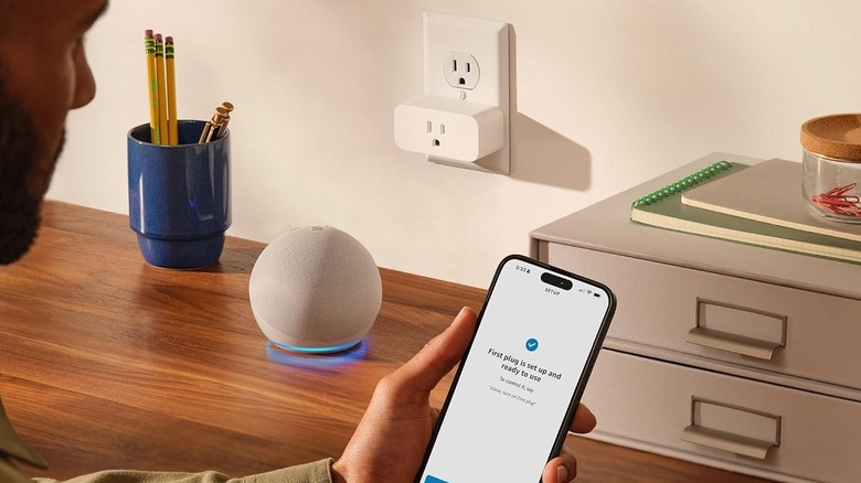 A person setting up an Amazon Smart Plug with an Echo speaker in the background