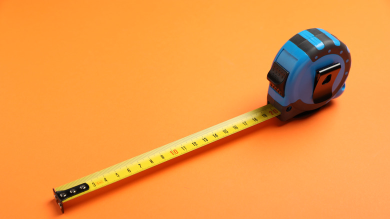 A blue tape measure on an orange background