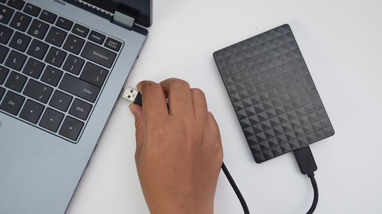 person plugging in a hard drive to their PC to perform a data backup