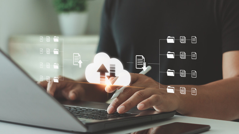 data syncing concept, person using laptop with hovering icons suggesting data is syncing across the internet