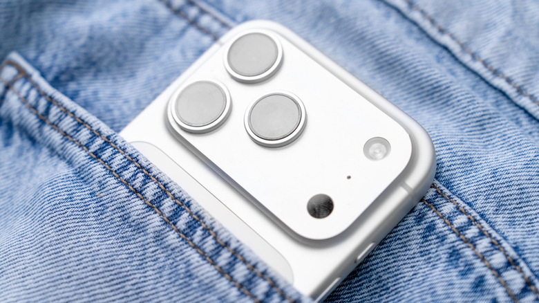 A three pack of camera lens protectors for a smartphone in a jeans pocket
