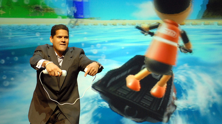 Former Nintendo of America CEO demoing the "Wii Sports Resort" "Power Cruising" game on stage by holding a Wii Remote and Nunchuk like jetski handles