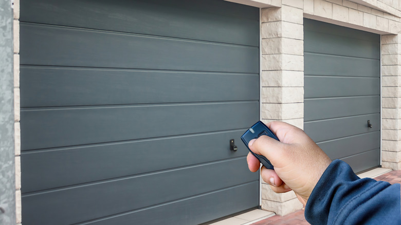 A person holding a remote in front of a garage door.