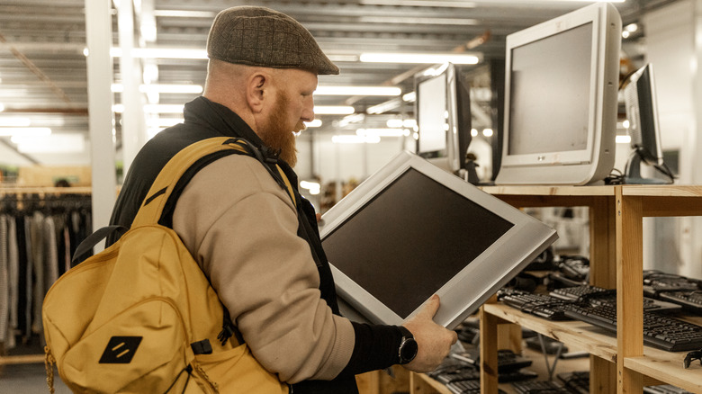 Person examining an old monitor in a thrift store