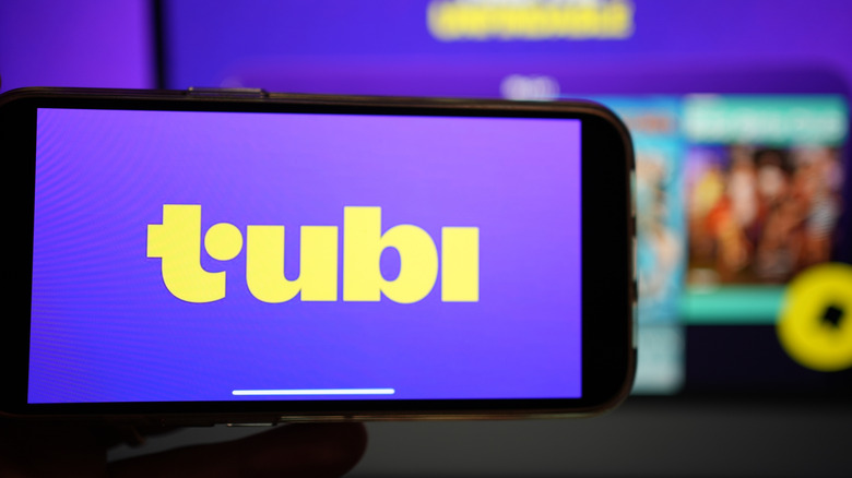 The Tubi TV logo on a phone in front of the TV