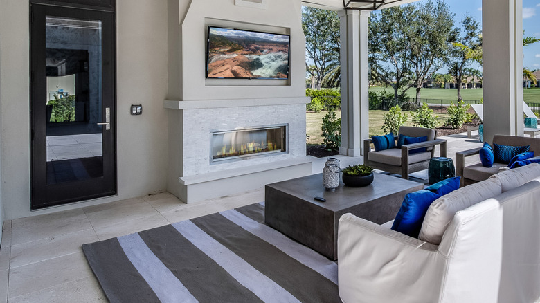A TV mounted above a fireplace in an outdoor patio setting.