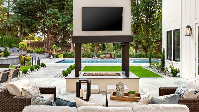 A TV mounted above a fireplace in an outdoor patio setting.