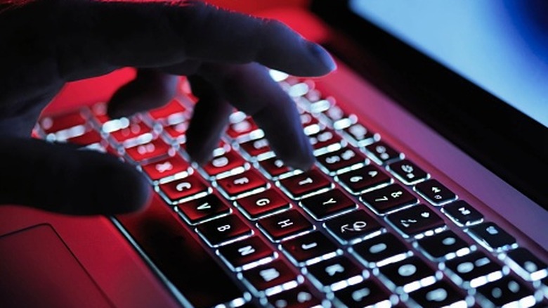 A close up of a hand typing on a backlit keyboard