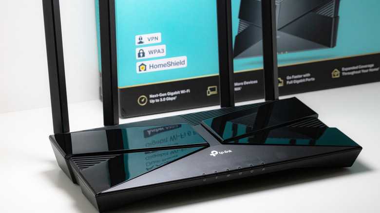 A TP-Link router on a desktop with a box nearby.