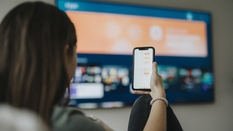 Looking at media on a phone with a smart TV in the background