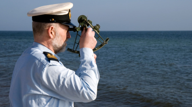 sailor using a sextant on the open seas to find celestial navigation data