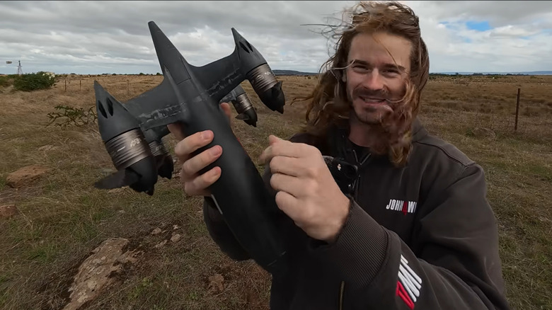 Ben Biggs, dressed in a black jacket, holds up the Blackbird drone with serrated rotors after its record breaking run.