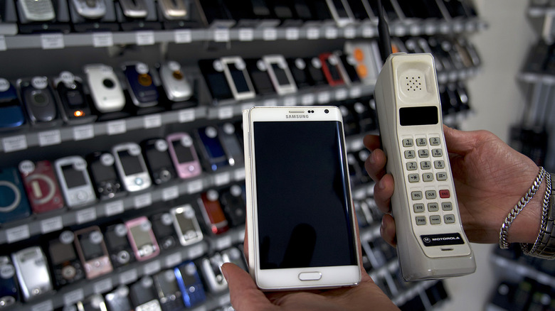 A Motorola DynaTAC 8000x held up beside a Samsung Galaxy Note Edge in a store.
