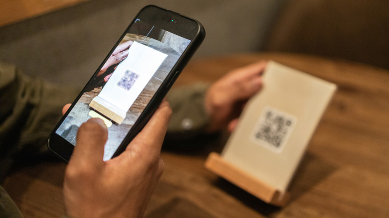 A man scanning a QR code with his phone to access a restaurant's menu