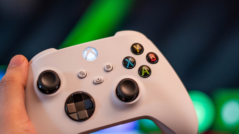 a gamer holds an Xbox controller in front of a TV screen