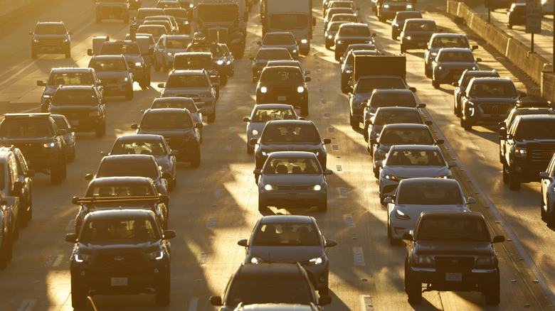 Backed up traffic in California as sun begins to set somewhere in background, climate concept