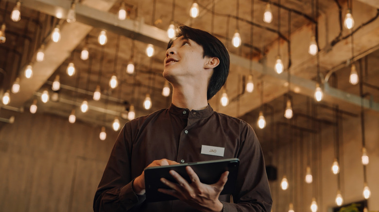A hotel staff member controls many smart light bulbs using a tablet