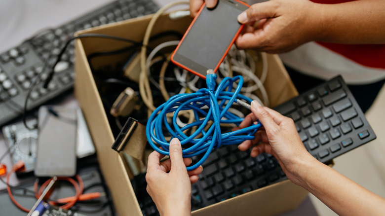 Two people putting old electronics into a cardboard box