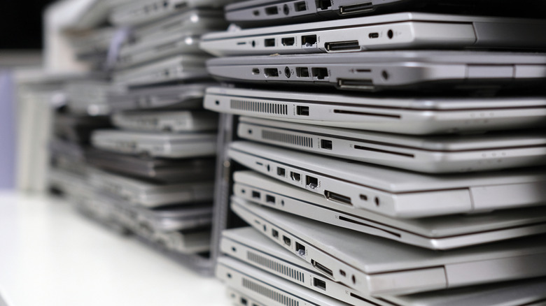 Stacks of silver laptops on a white surface