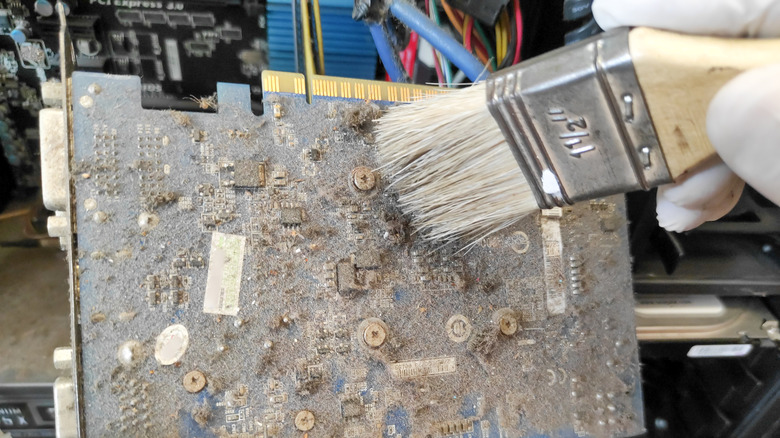 Man cleaning dusty graphics card with hand brush
