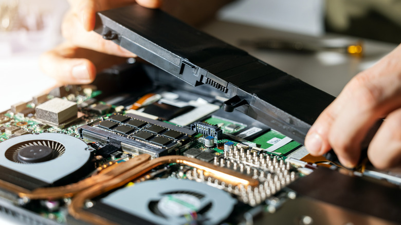 Person accesing laptop internals and is removing battery