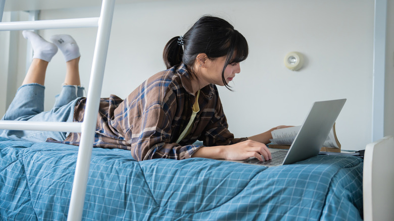 Woman using a laptop while lying in bed