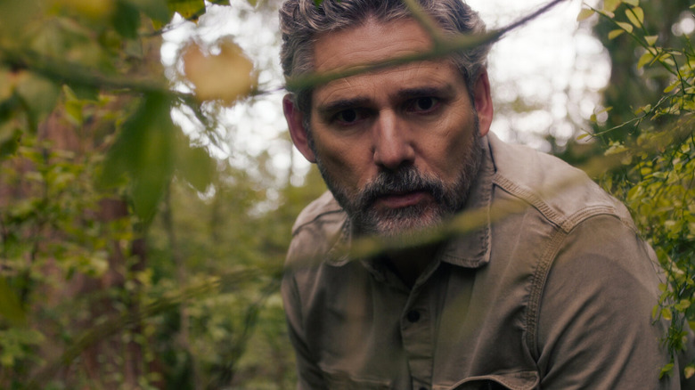 Actor Eric Bana peering into the woods in Netflix's Untamed