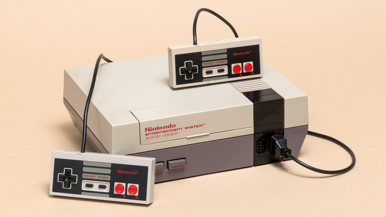 a Matte NES console with two controllers on a peach background
