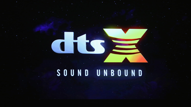 DTS:X logo lit up and shown on a theater screen in the dark.