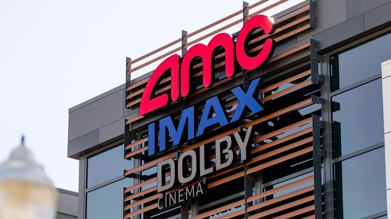 AMC theaters logo on a sign with IMAX and Dolby Cinema tags below.