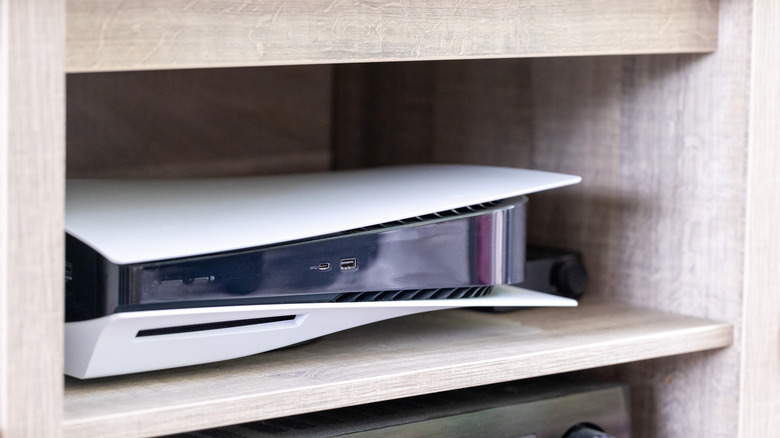 PlayStation 5 console sitting inside enclosed TV unit shelf