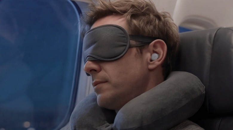 Man wearing Soundcore Sleep earbuds on a plane
