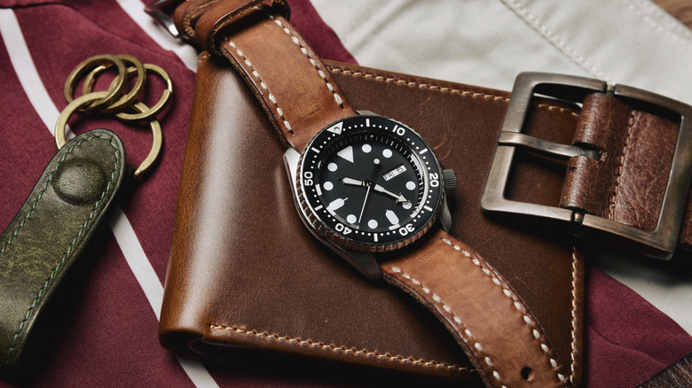 A wrist watch on top of a wallet.