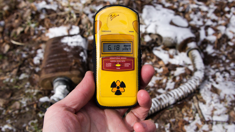 A person holding a radiation detector.