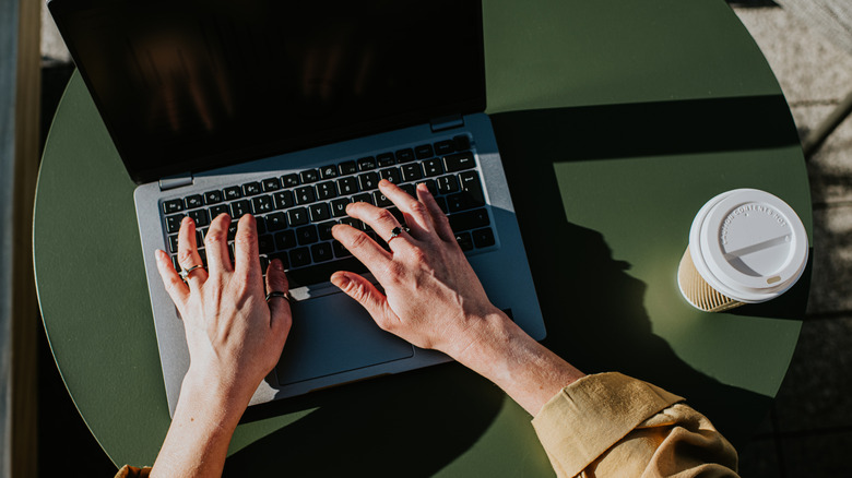 A person typing on a laptop placed on a table.