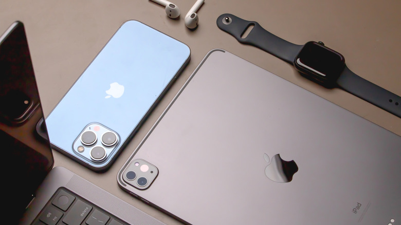 MacBook, iPhone, iPad, Apple Watch, and AirPods, on a table.