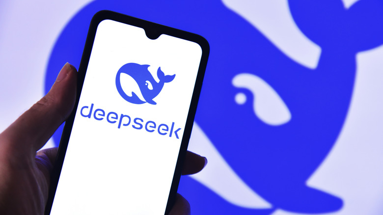 Hand holding phone showing the DeepSeek logo in front of a larger logo